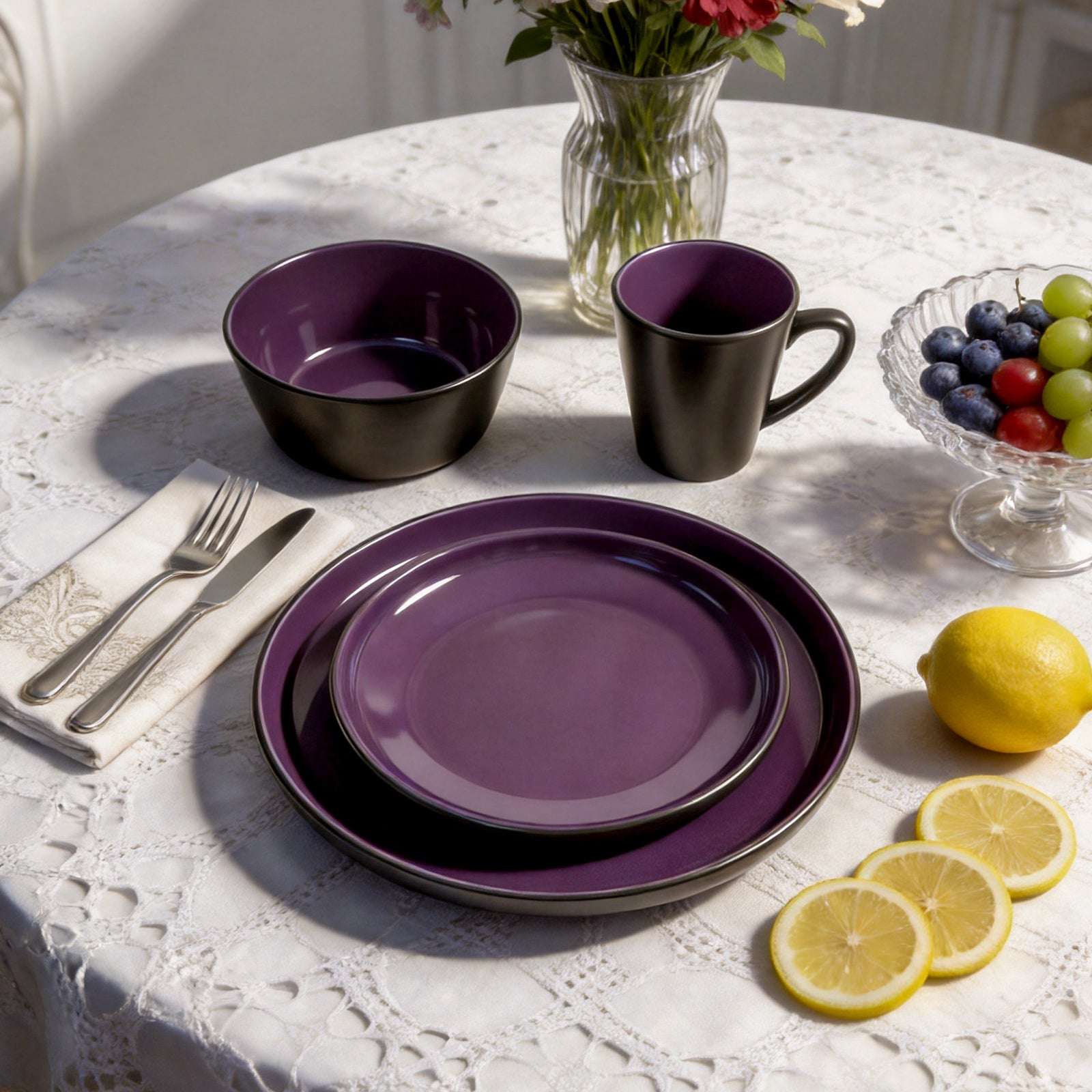 Purple dinnerware set on a table with lemons and grapes