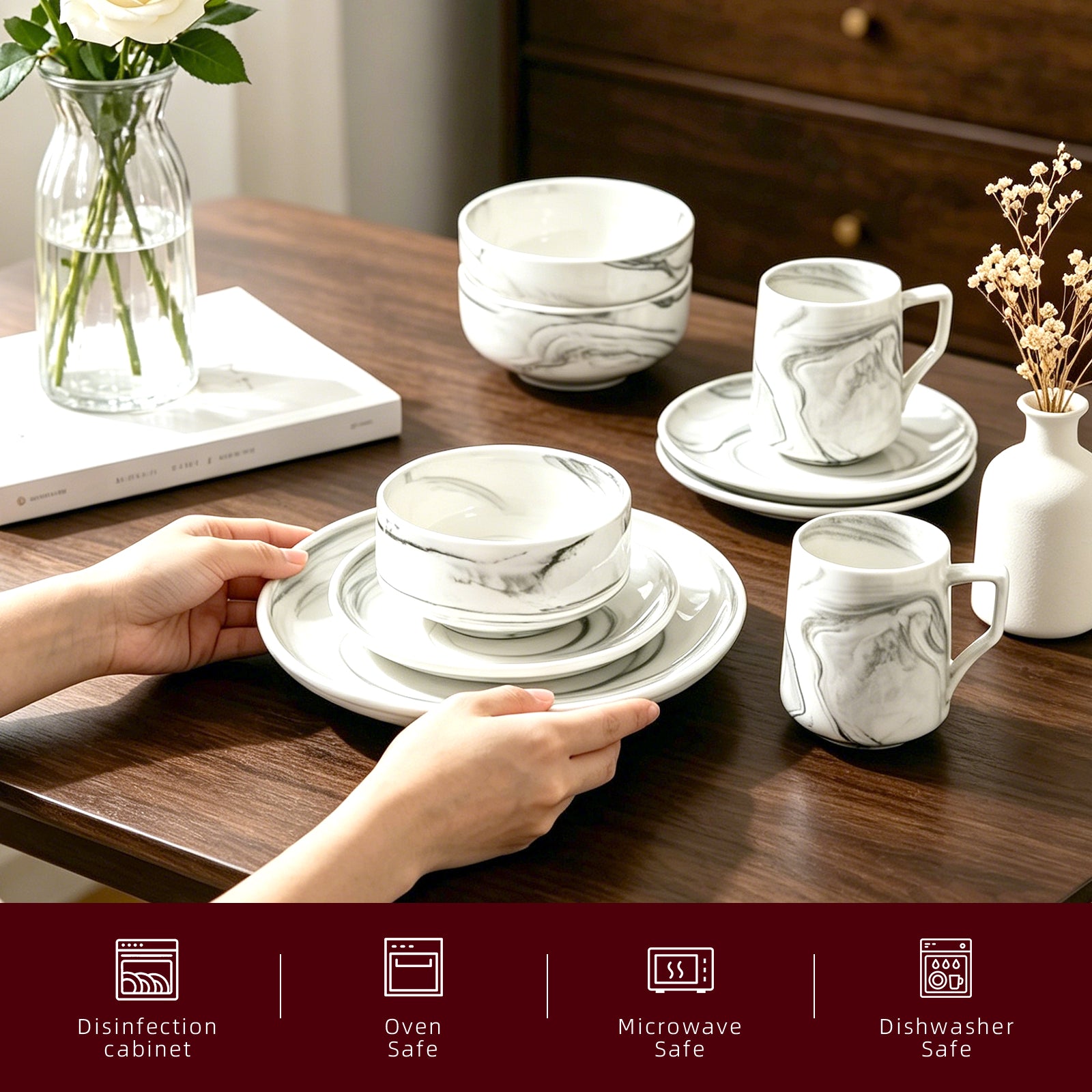 A set of white ceramic tableware with a gray marble pattern, including bowls, plates, and mugs, arranged on a dark wooden table. A person's hands are holding a stack of plates in the foreground.