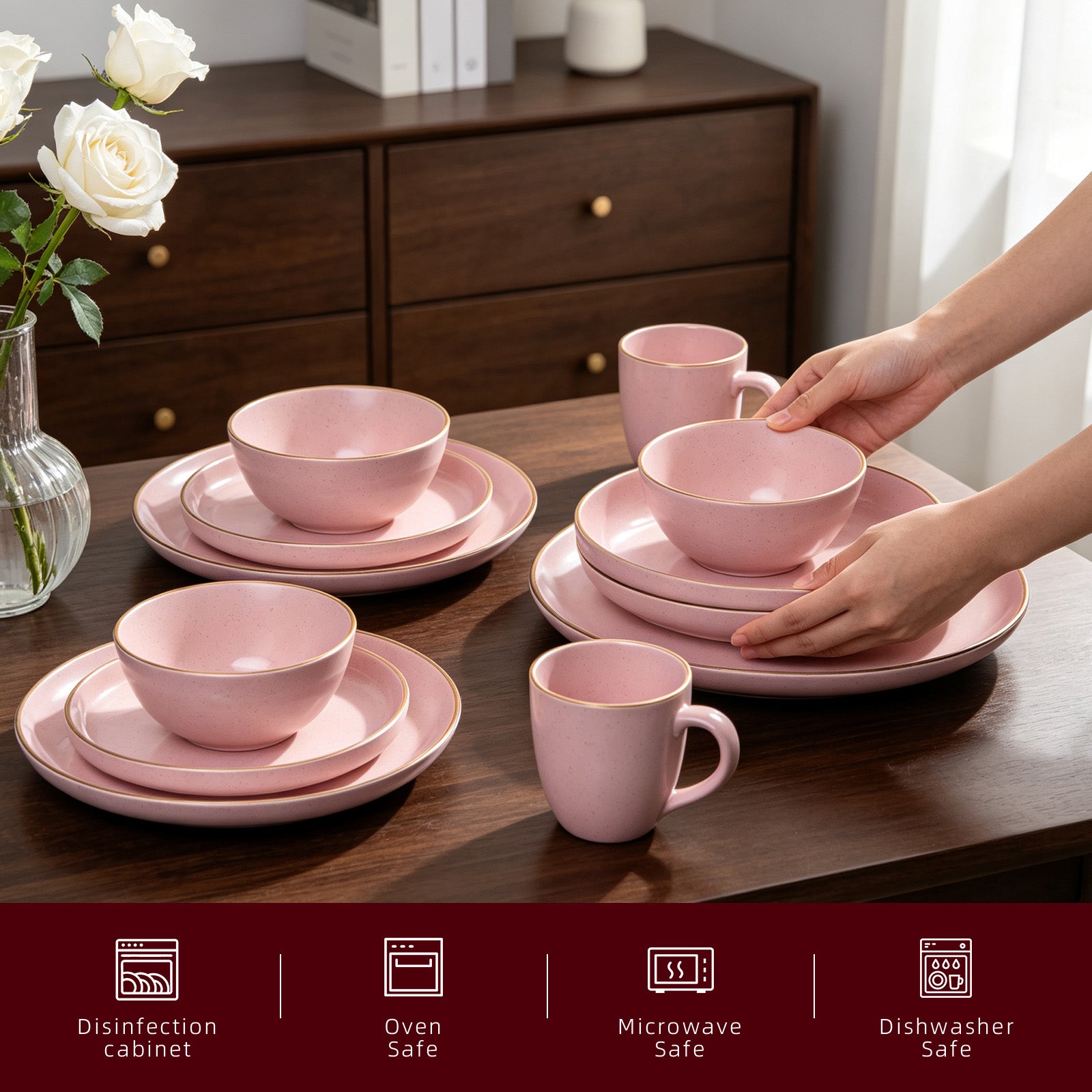 Pink ceramic dinnerware set on a wooden table with a vase of white roses.