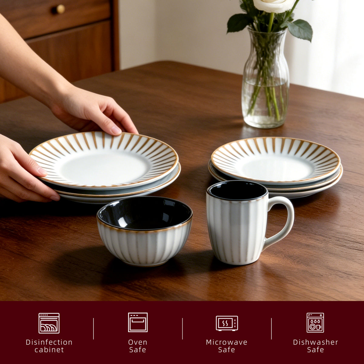A set of ceramic tableware on a wooden dining table, including white plates and bowls with gold striped rims, a white mug with a dark interior, and a person's hands placing a stack of plates. A vase with white flowers sits in the background, and a dark red informational banner at the bottom lists dishwasher, oven, microwave, and disinfection safety features.