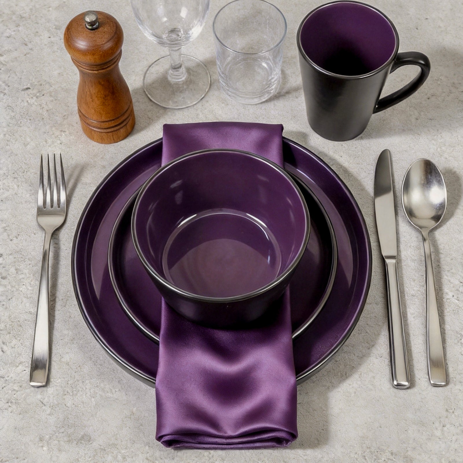 Purple dinnerware set with silverware on a gray surface