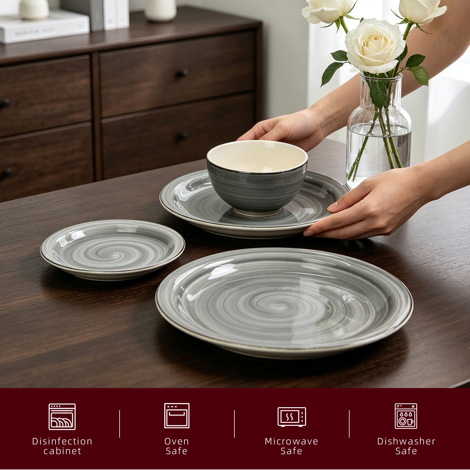 Gray and white swirled ceramic dinnerware set including plates, a bowl, and a saucer, being arranged on a dark wooden table by a person whose hands are visible. A glass vase with white roses sits in the background, and a dark red banner at the bottom lists product features like disinfection cabinet, oven safe, microwave safe, and dishwasher safe.