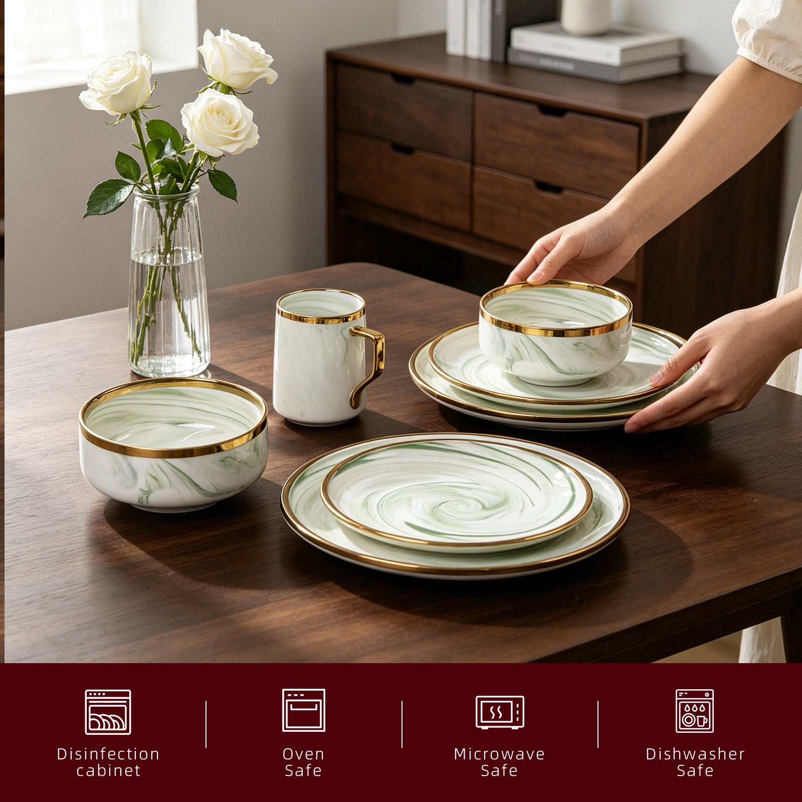 A ceramic dinnerware set with a white and light green marble swirl pattern and gold trim, shown on a dark wooden table with a person's hands placing a bowl on a stack of plates. A glass vase with white roses and a dark wood cabinet are in the background.