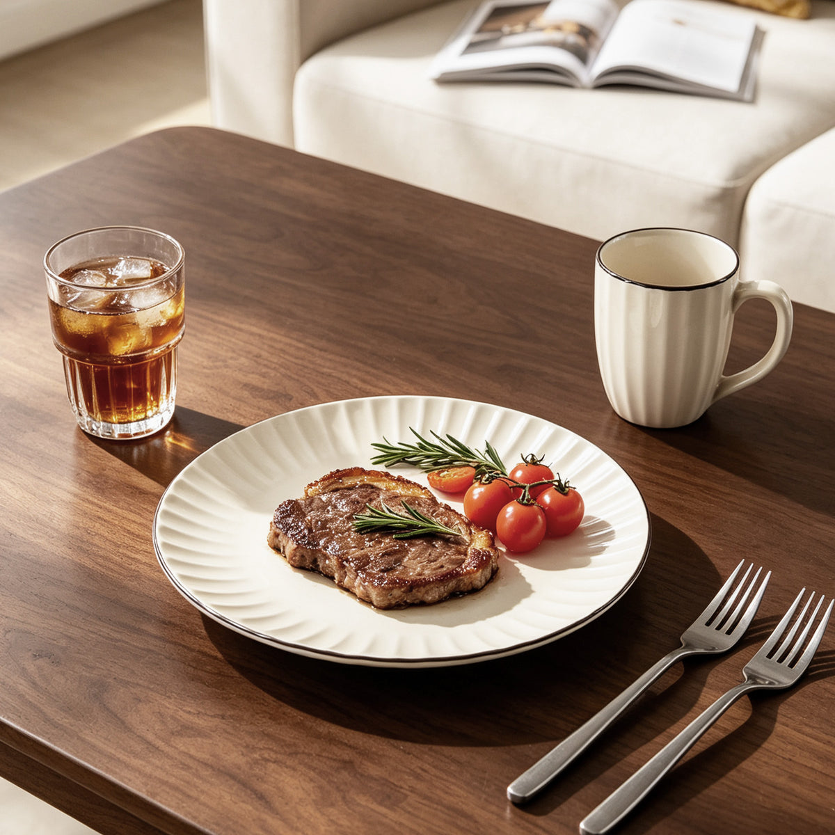 A white ribbed ceramic plate with a scalloped rim, styled with a cooked steak, cherry tomatoes, and a rosemary sprig on a dark wood table. A glass of iced coffee, a cream-colored mug with a thin black rim, and two forks are arranged around it in a cozy dining setting.